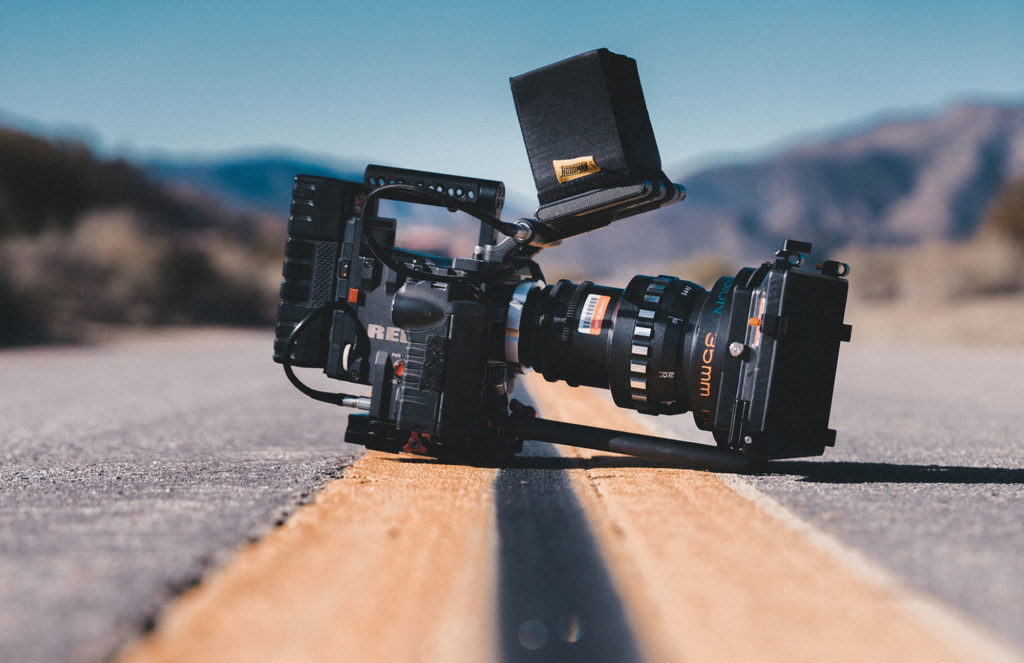 A high-end professional camera sits on a road